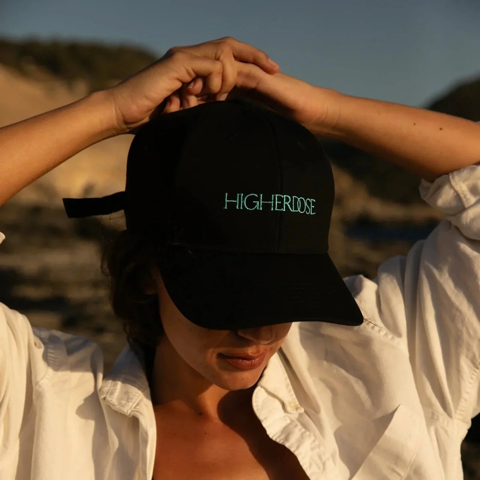 woman wearing HigherDOSE red light hat on the beach on nanaka.co