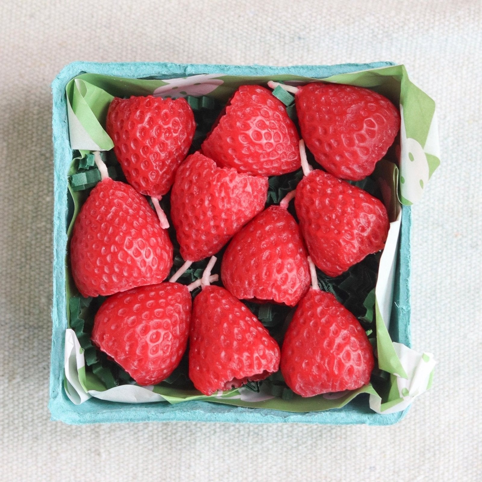 Beeswax strawberry birthday candles by Happy Organics arranged on a cake