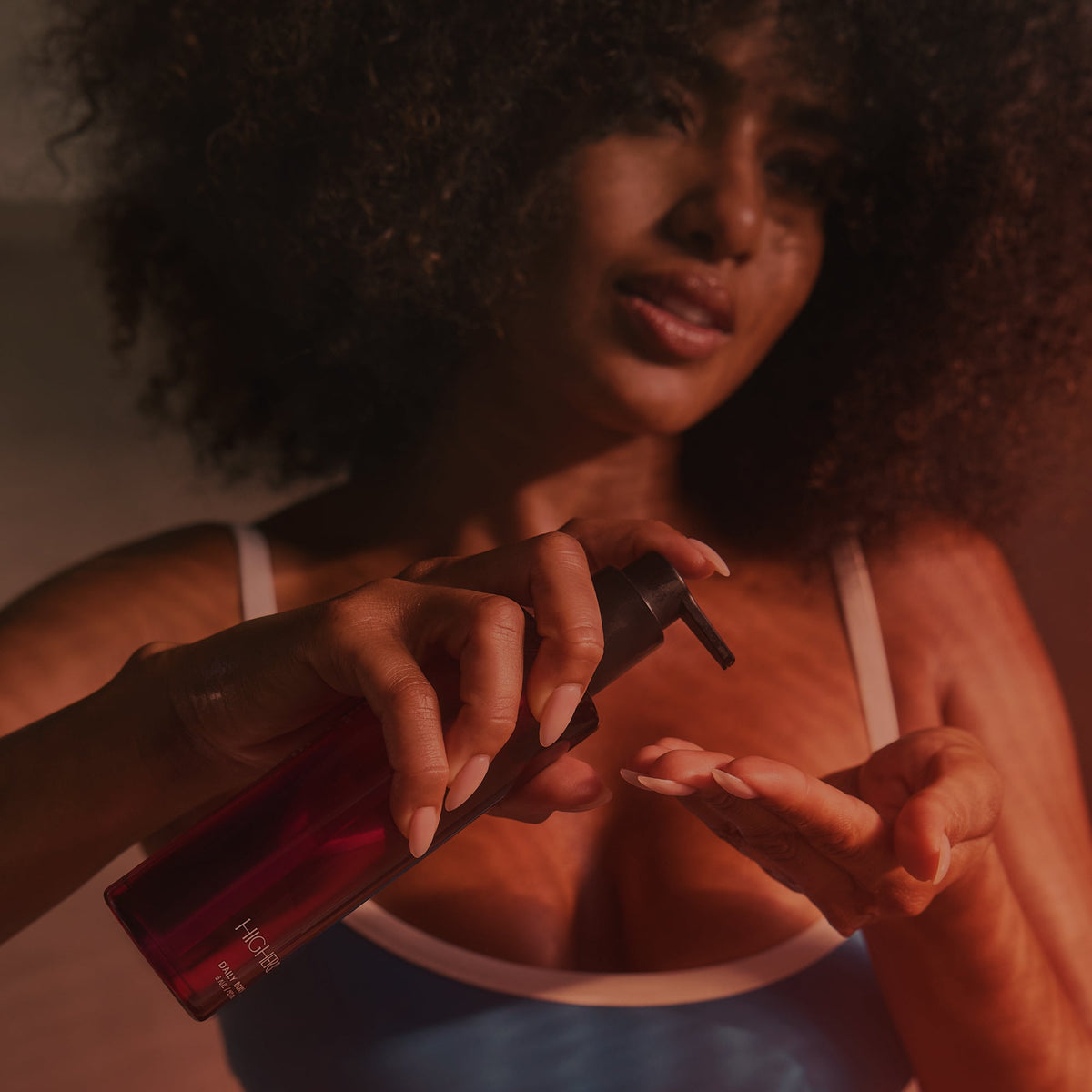 Woman holding the HigherDOSE Daily Body Oil bottle over her chest