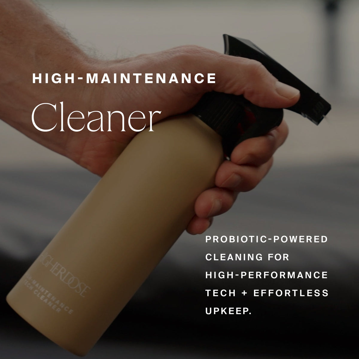 Hand gripping the HigherDOSE High-Maintenance Cleaner spray bottle: probiotic-powered cleaning for high-performance tech