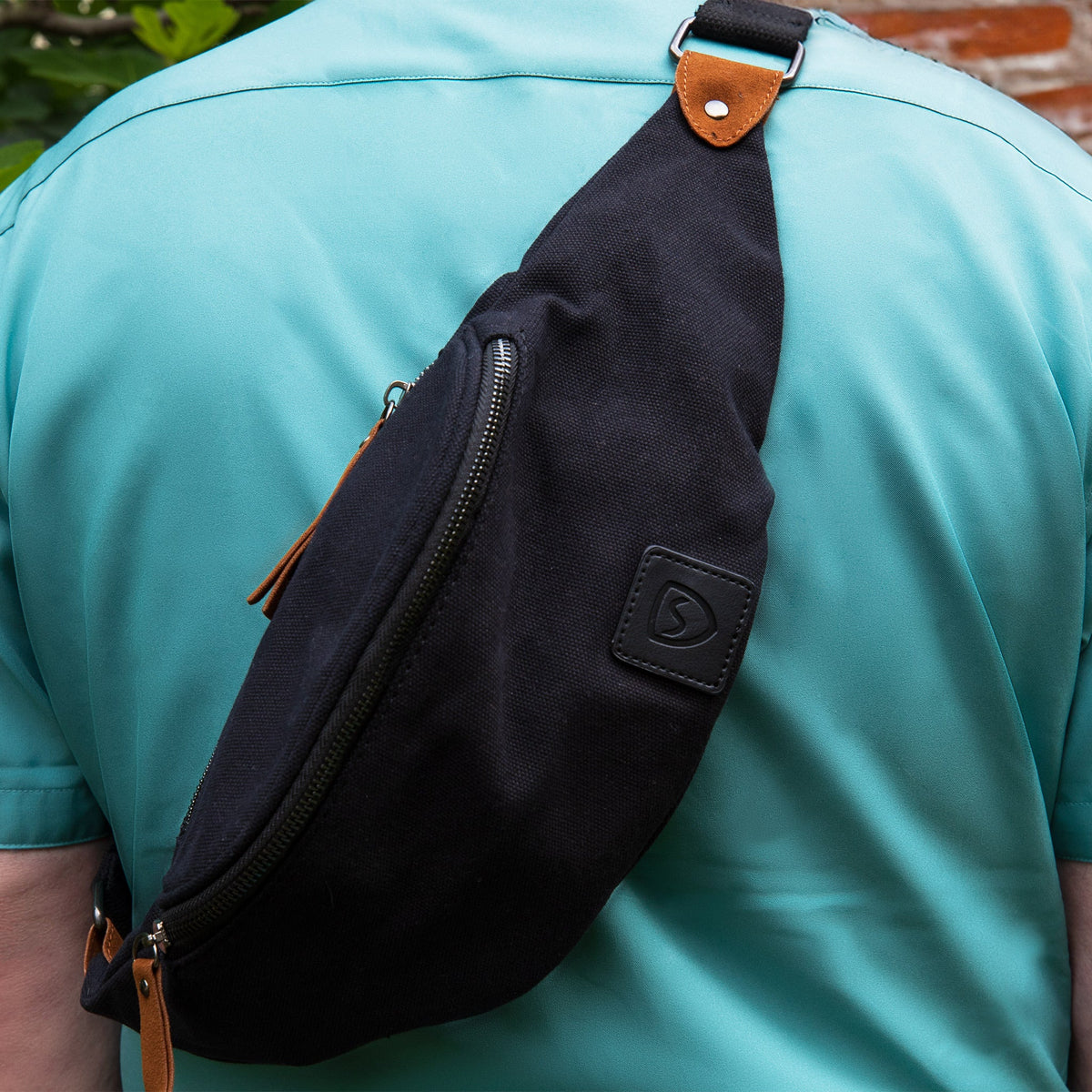 Man in a teal shirt wearing the Shield Your Body Canvas Traveler Fanny Pack across his chest