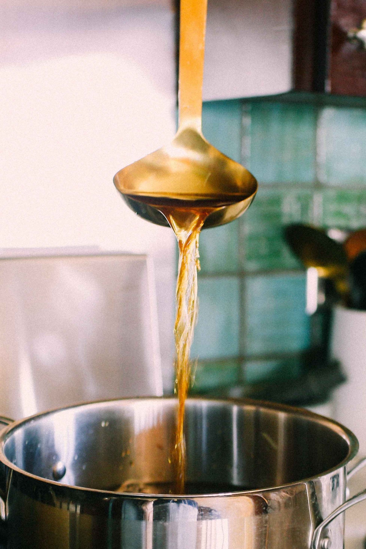 Ladle pouring brewed chaga into a pot of liquid, preparing Sun Potion Chaga