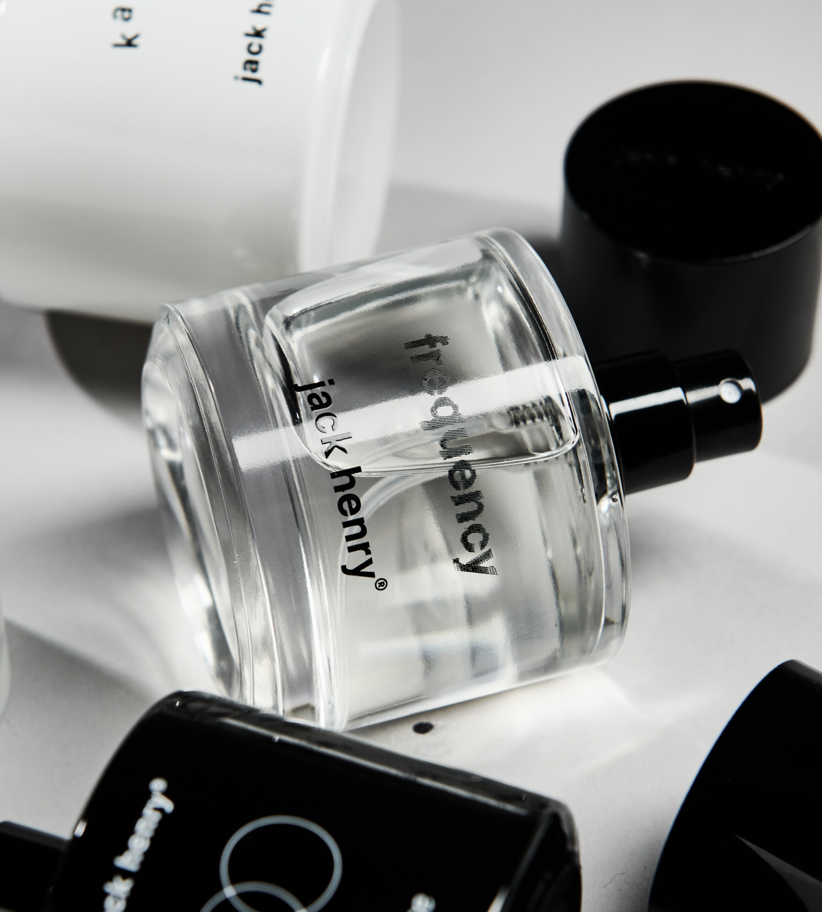 Jack Henry Frequency bottle tilted on a white surface with its cap beside it