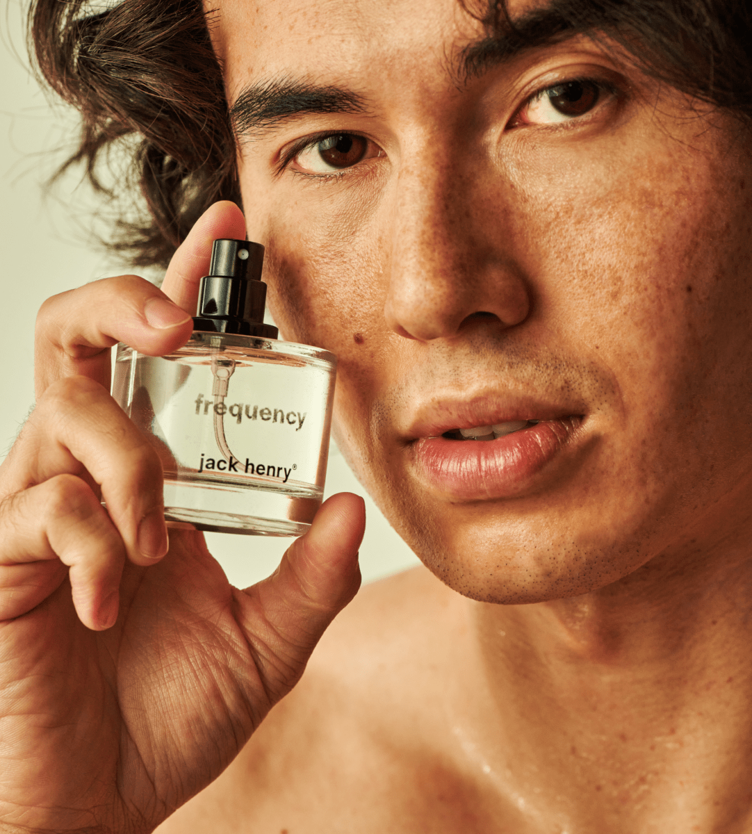 Man holding a bottle of Jack Henry Frequency beside his face