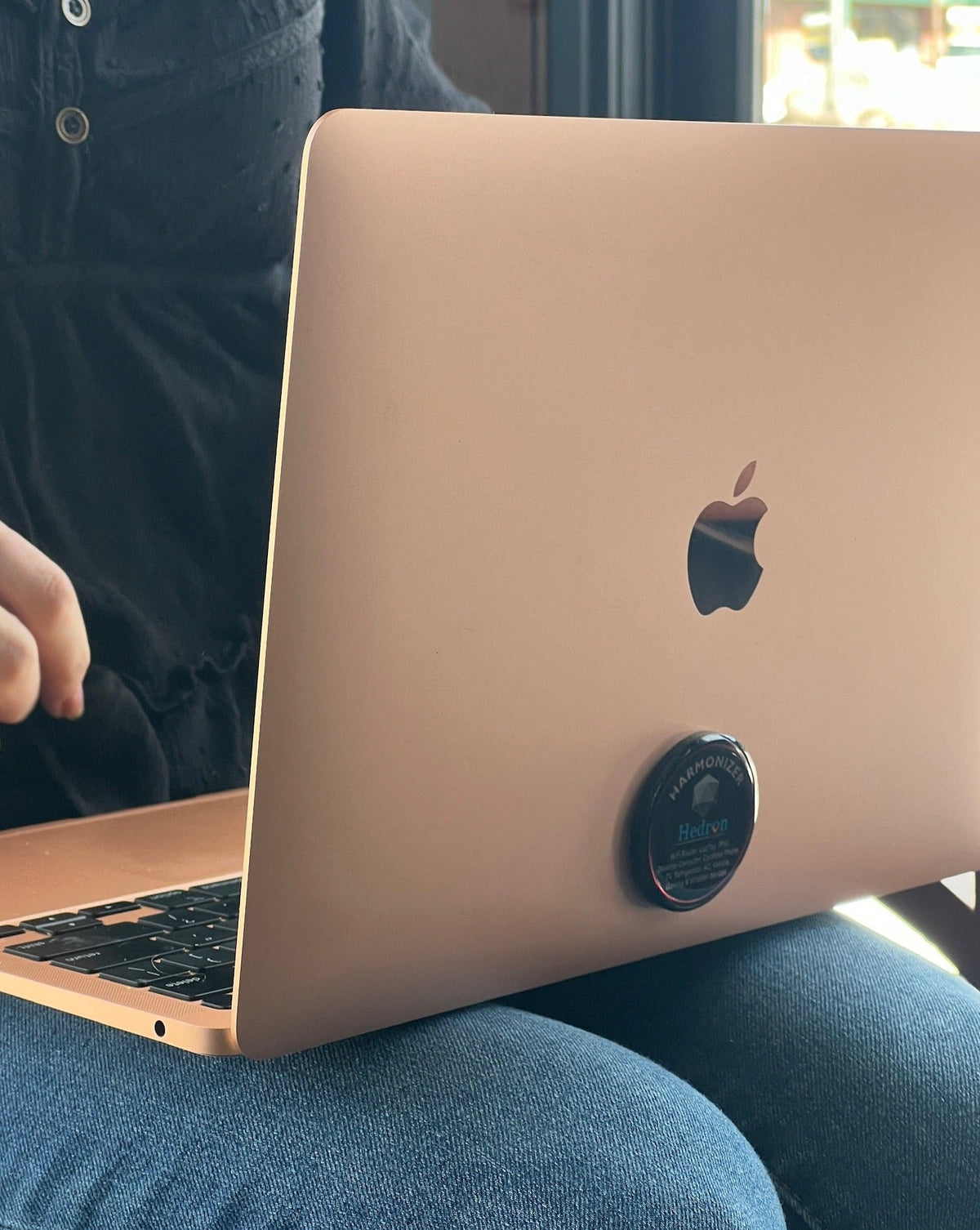 Hedron Life Source Harmonizer sticker on the back of a rose gold laptop