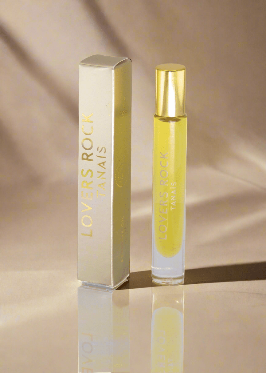 TANAÏS Lovers Rock Perfume Oil roll-on bottle beside its gold box on a beige background