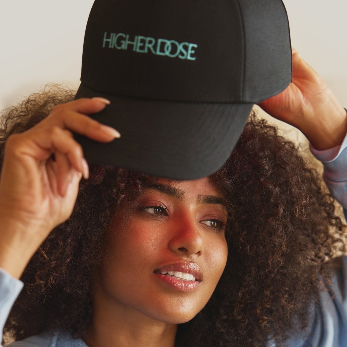 Woman with curly hair adjusting the HigherDOSE Red Light Hat
