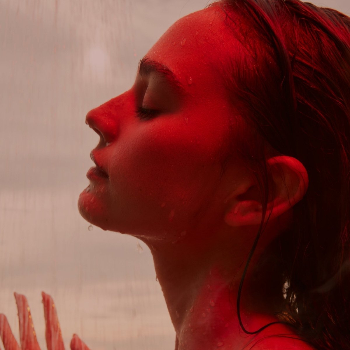 Woman in a red-lit shower, face and neck close-up, HigherDOSE Red Light Showerhead Filter