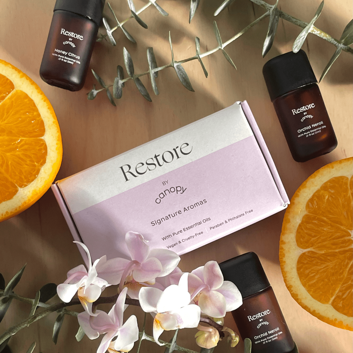 Canopy Restore Aroma Kit box beside orange slices, orchids and aroma bottles