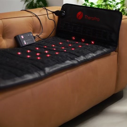 Therasage TheraPro pad laid out on a leather couch with its controller
