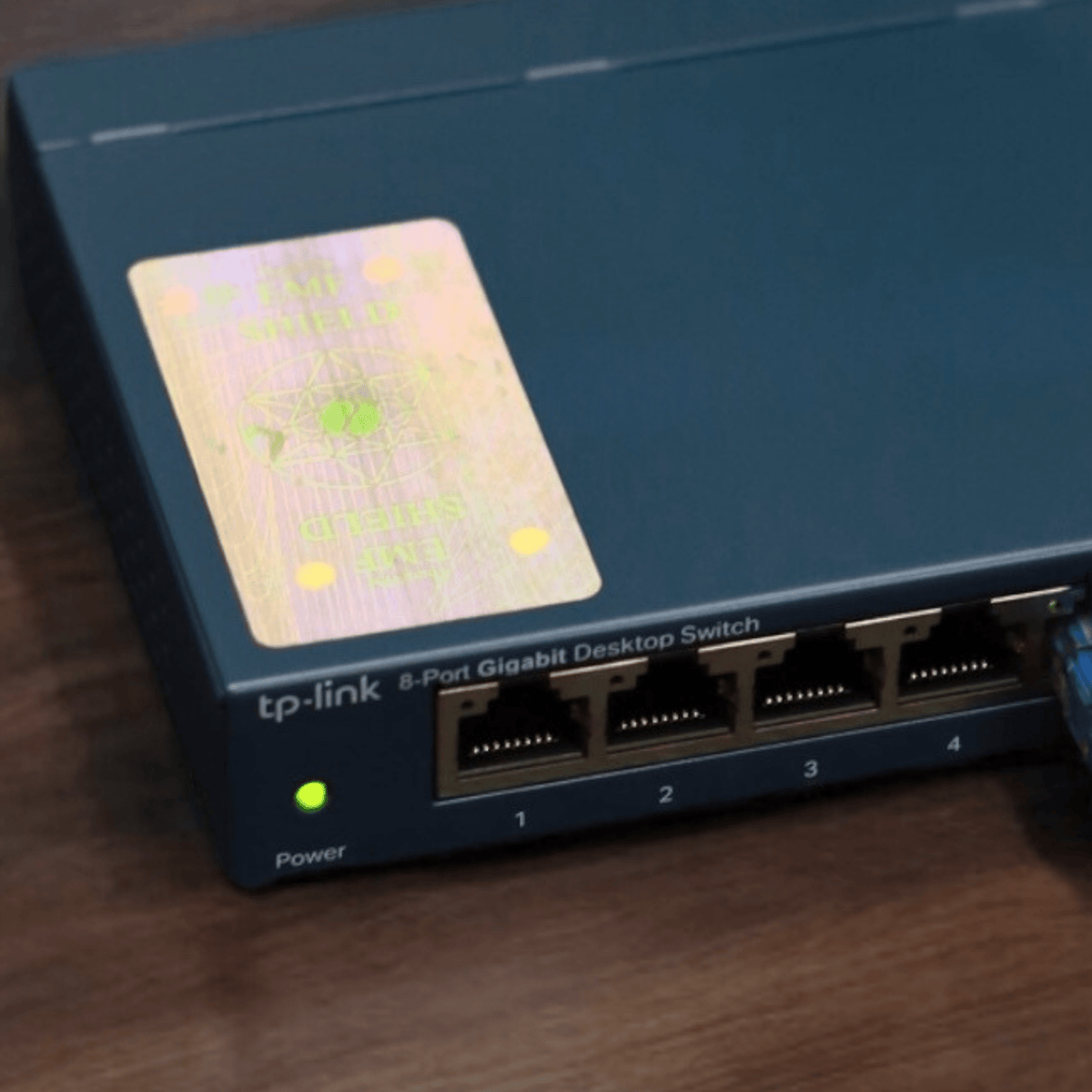 Close-up of a Therasage TheraProtect holographic EMF sticker on an 8-port network switch
