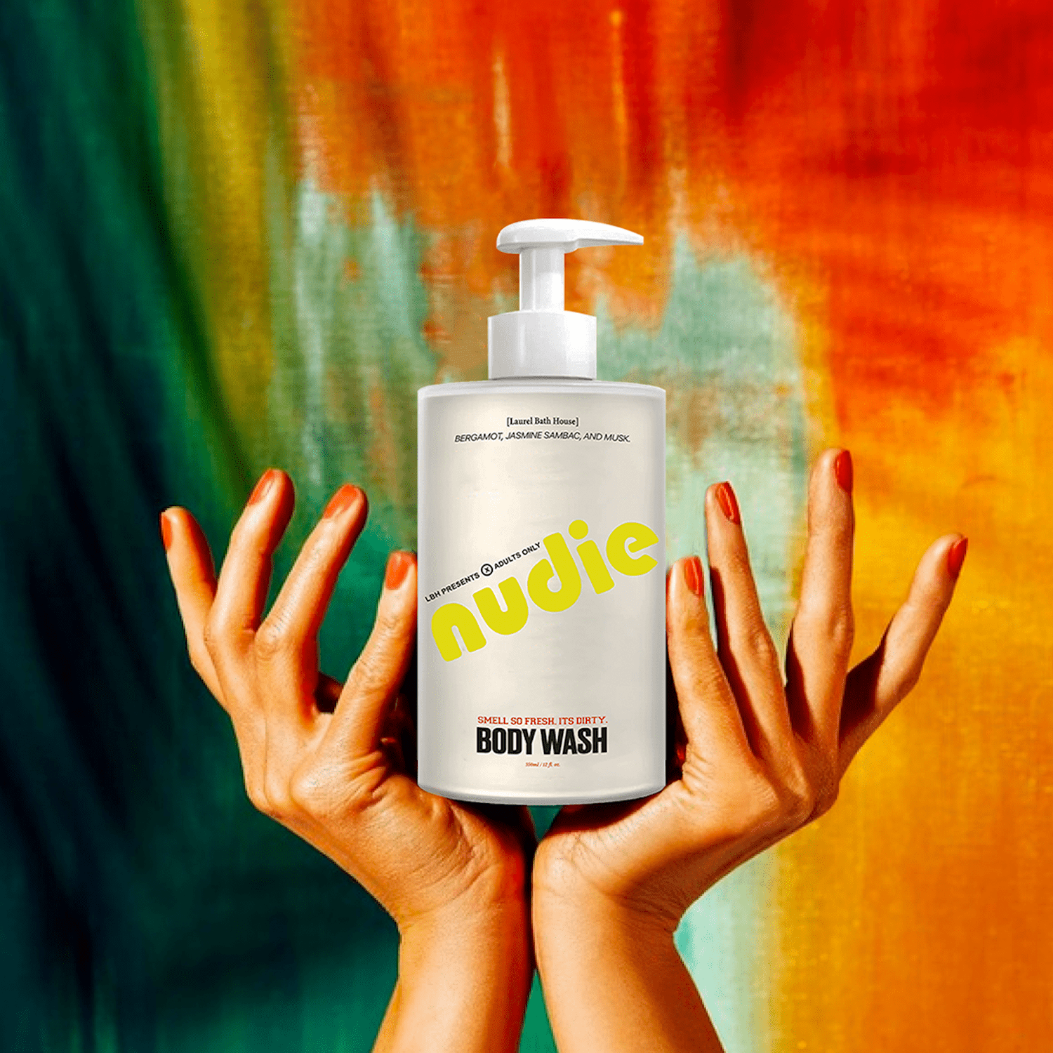 Two hands holding up a bottle of Nudie body wash by Laurel Bath House against a colorful painted background in green, orange, and red