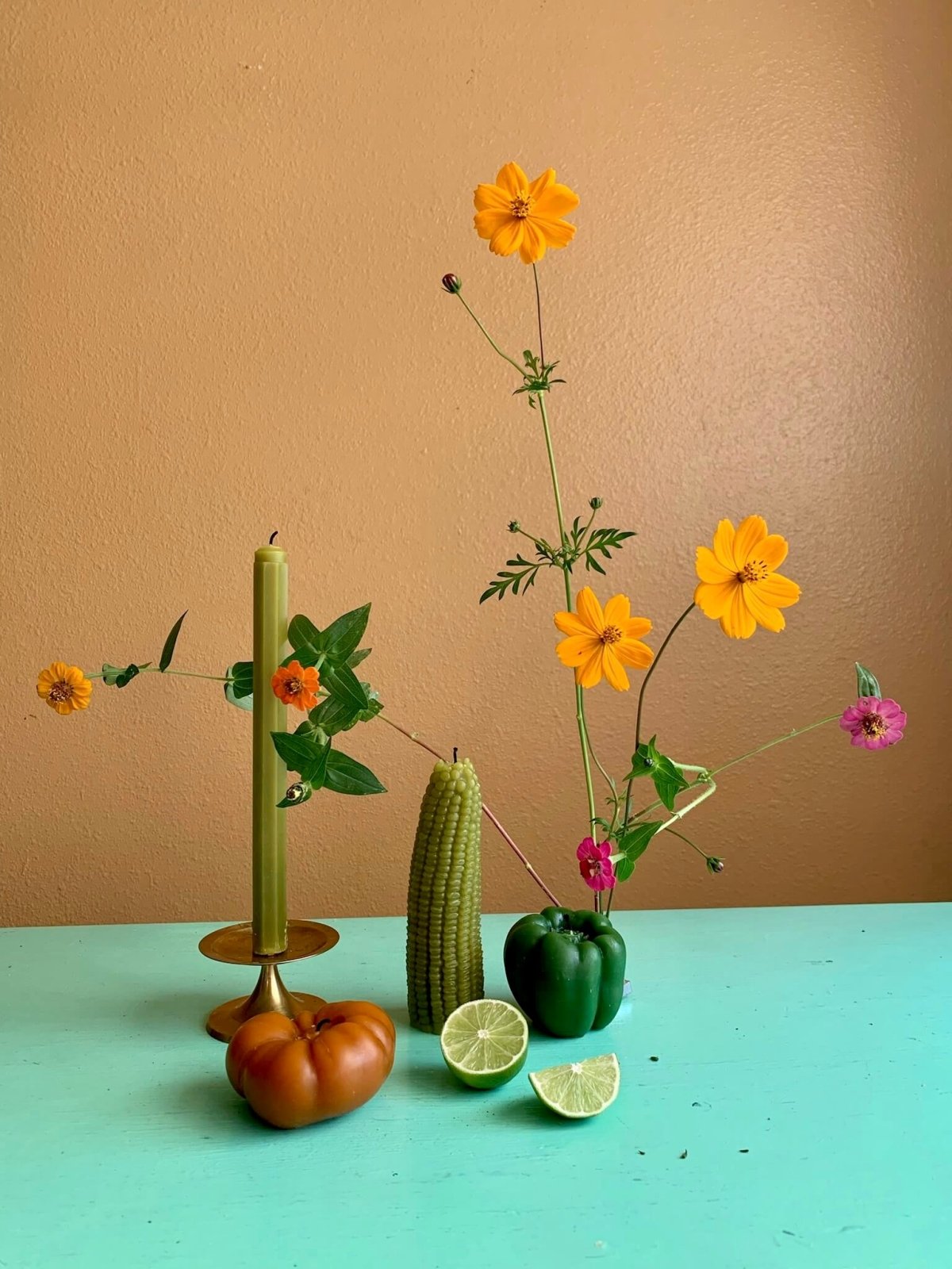 Happy Organics beeswax candles styled with wildflowers on a teal table, handmade in Los Angeles
