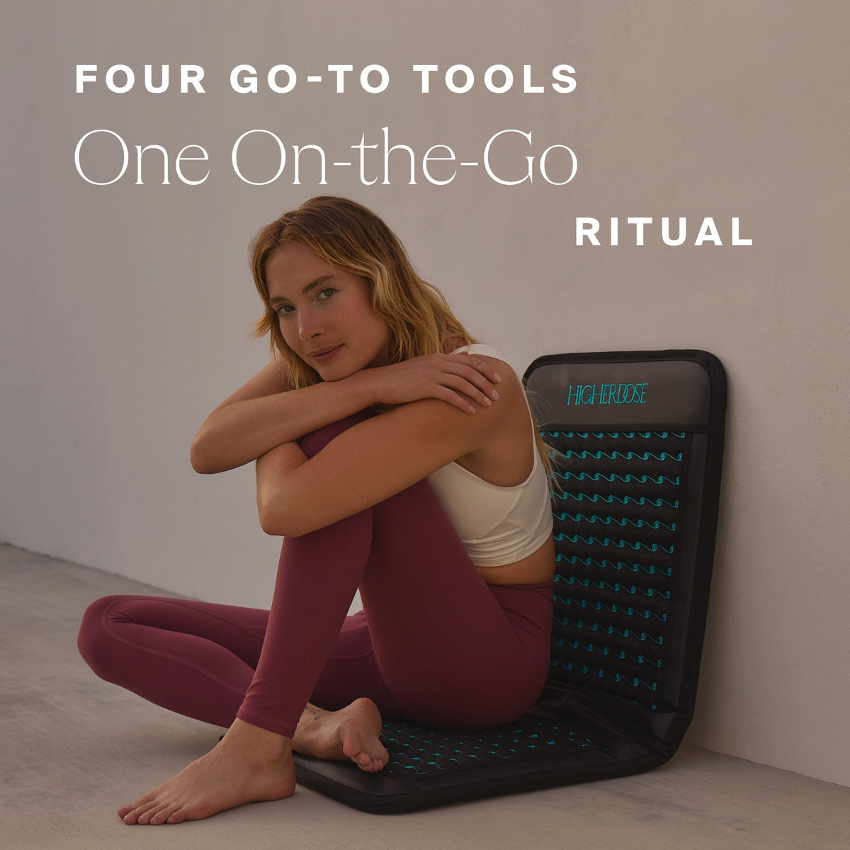 Woman hugging her knees on the HigherDOSE Infrared PEMF Go Mat on a floor: four go-to tools, one on-the-go ritual
