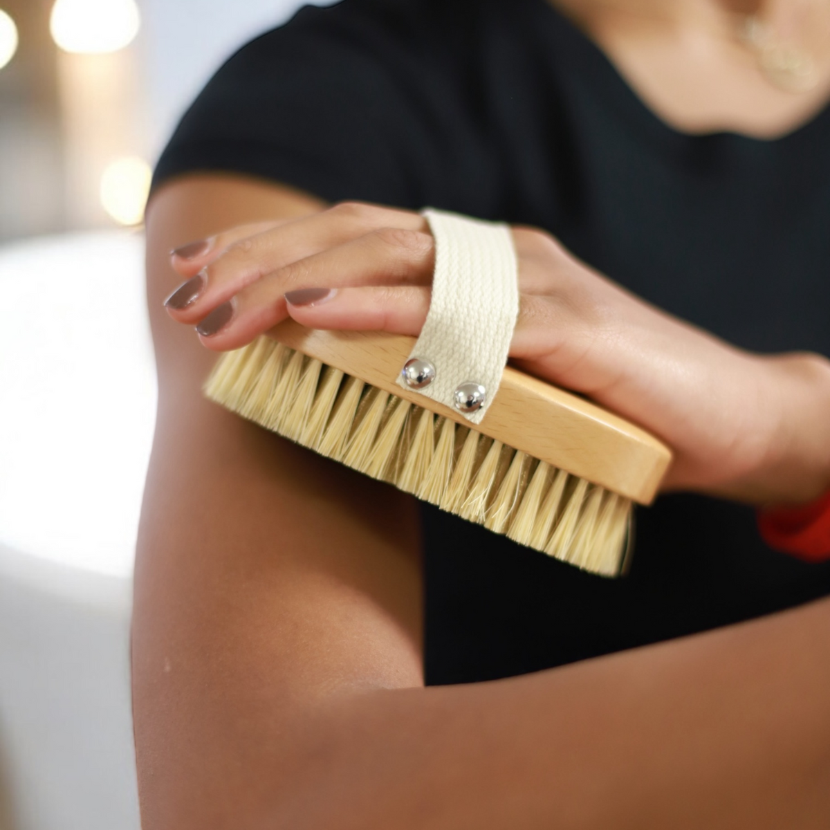 Woman using the Therasage TheraBrush dry brush on her upper arm