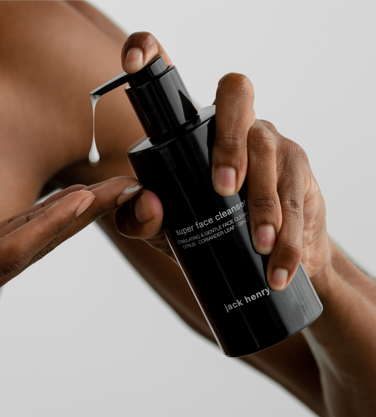 Hand pumping Jack Henry Super Face Cleanser onto a forearm