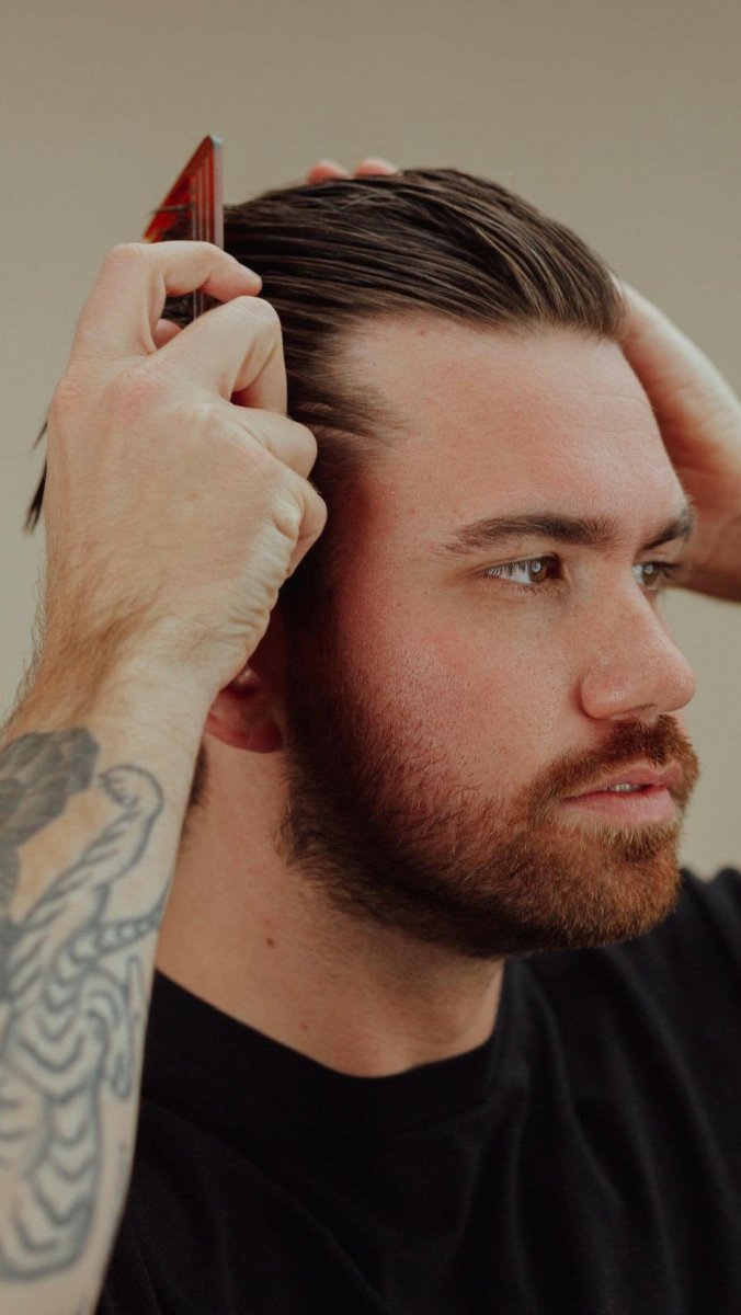 Man with a beard combing back his hair, styled with Firsthand Supply All-Purpose Pomade