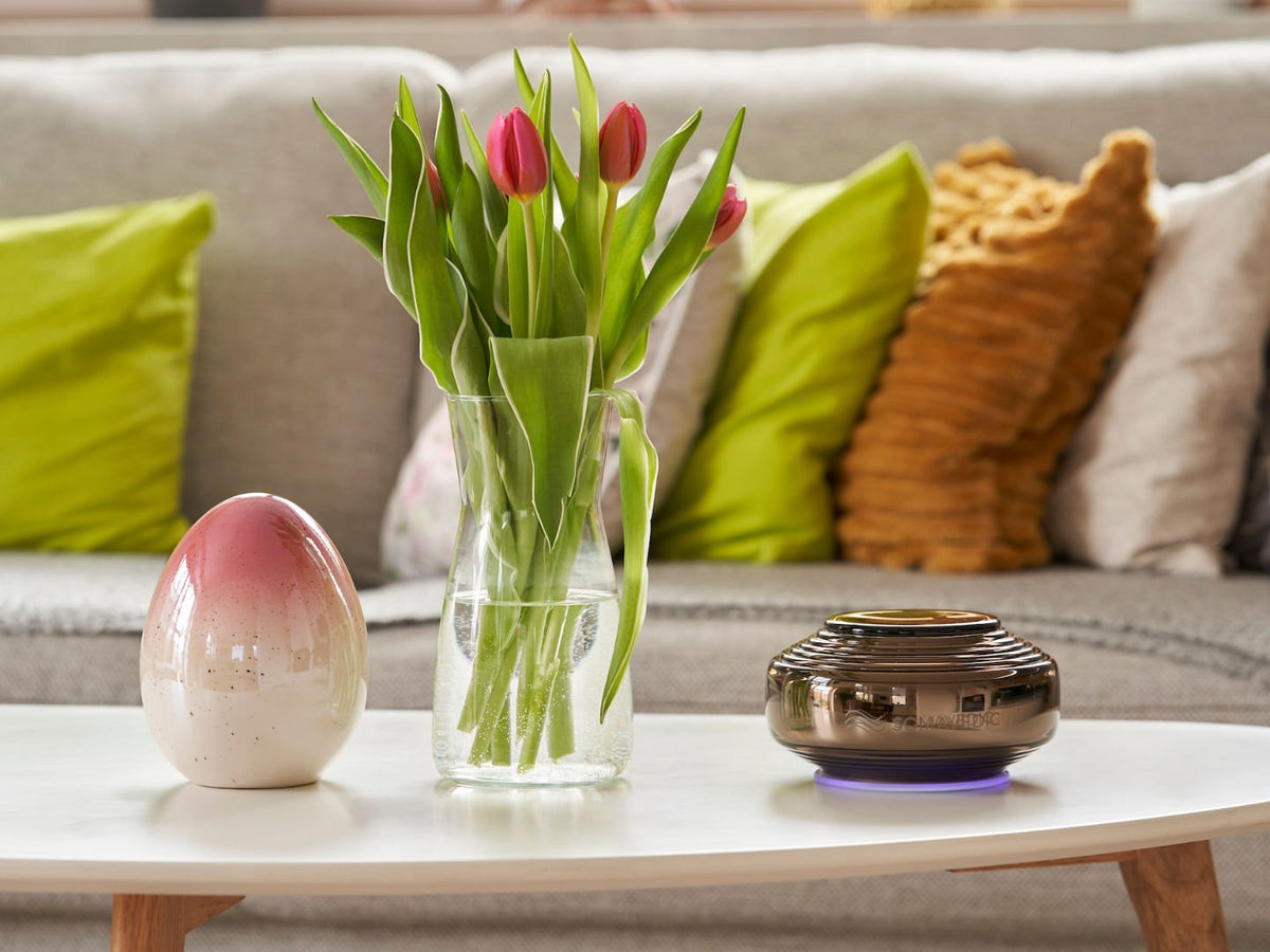 Somavedic Anthracite on a white coffee table beside tulips and a ceramic egg