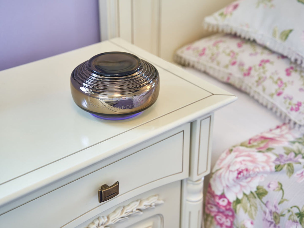 Somavedic Anthracite on a white bedside table beside floral bedding
