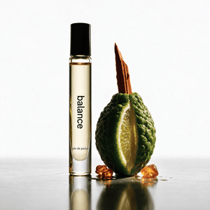 Jack Henry Balance roll-on fragrance beside a kaffir lime and a piece of wood