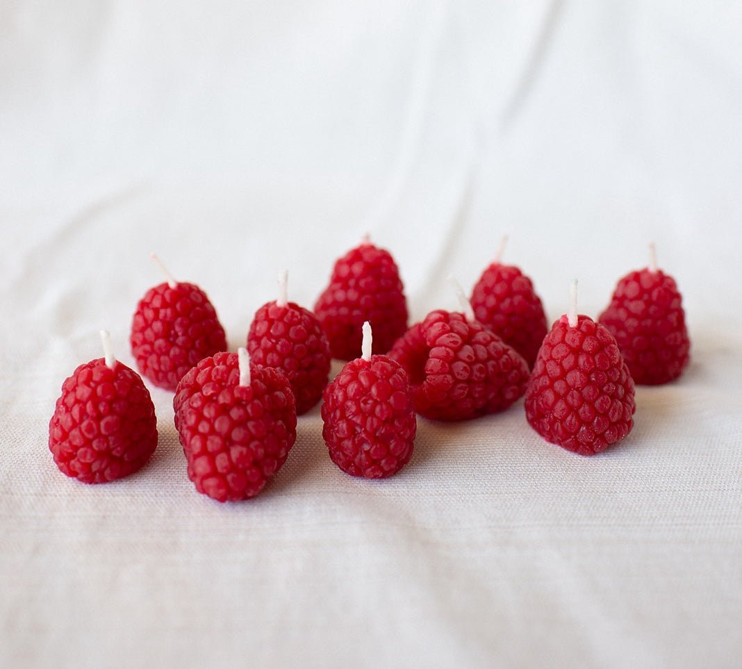 Happy Organics Raspberry Beeswax Birthday Candles scattered on a white cloth