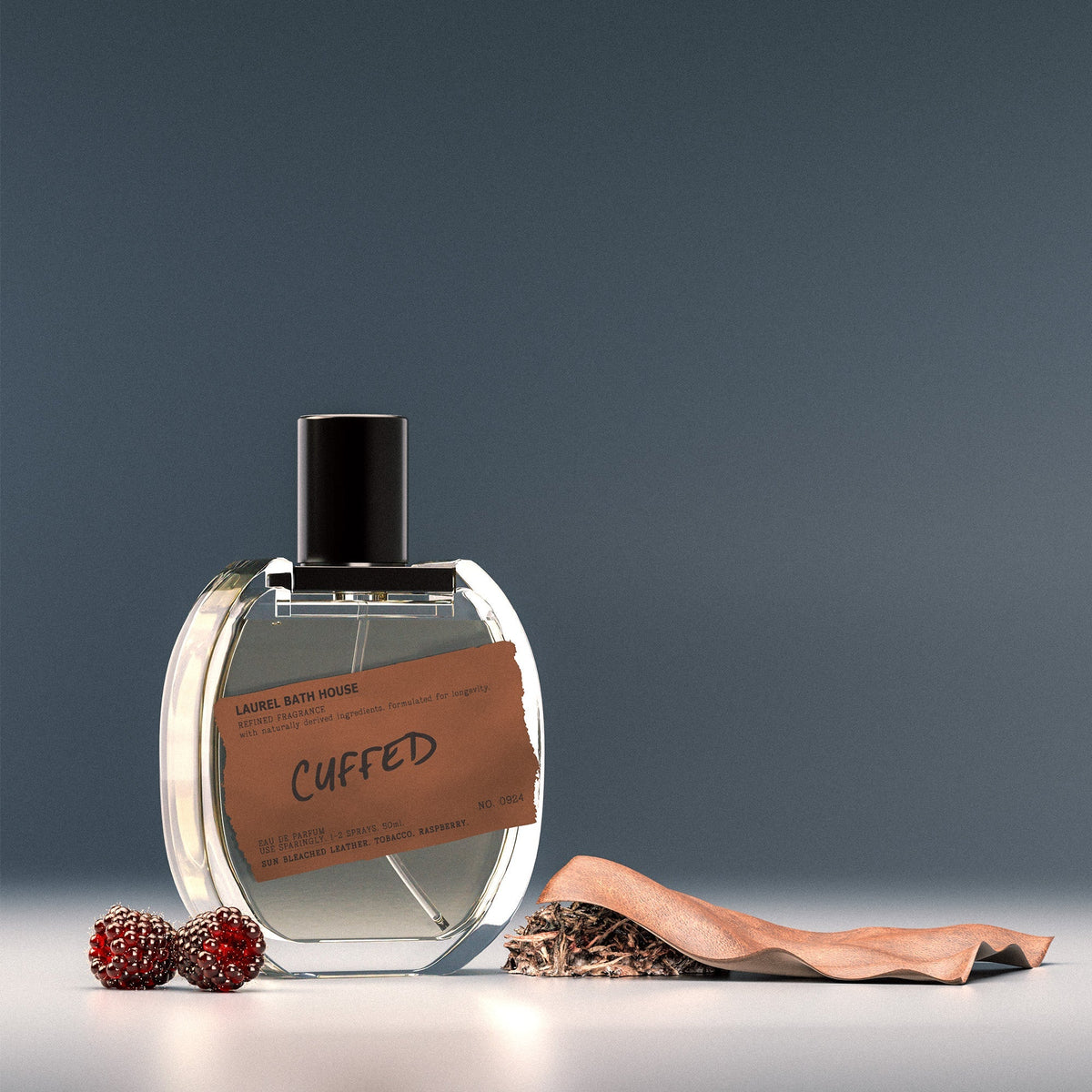 Laurel Bath House Cuffed eau de parfum beside raspberries and a piece of leather