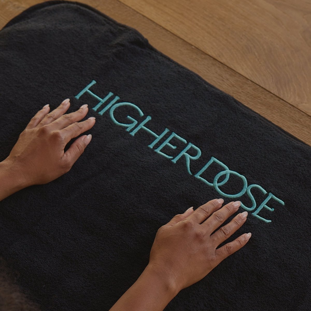 Hands resting on the HigherDOSE towel topper over the PEMF Pro Mat