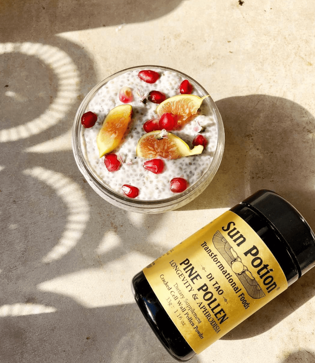 Sun Potion Pine Pollen jar lying on its side beside a chia pudding with figs and pomegranate