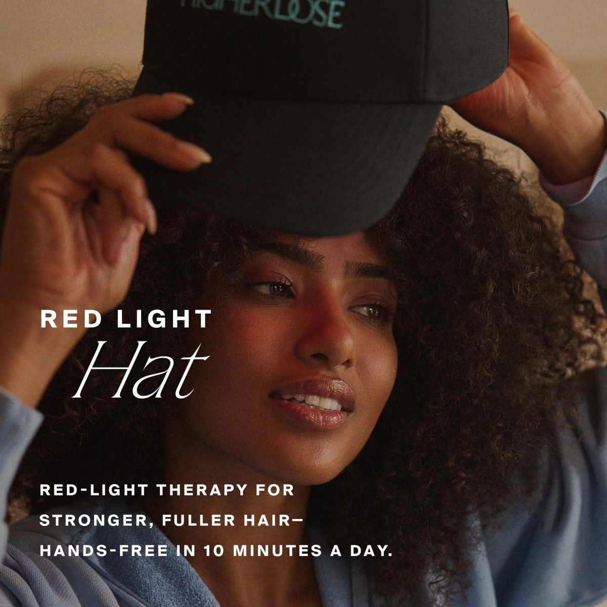 Woman holding the brim of the HigherDOSE Red Light Hat: red-light therapy for stronger, fuller hair in 10 minutes a day
