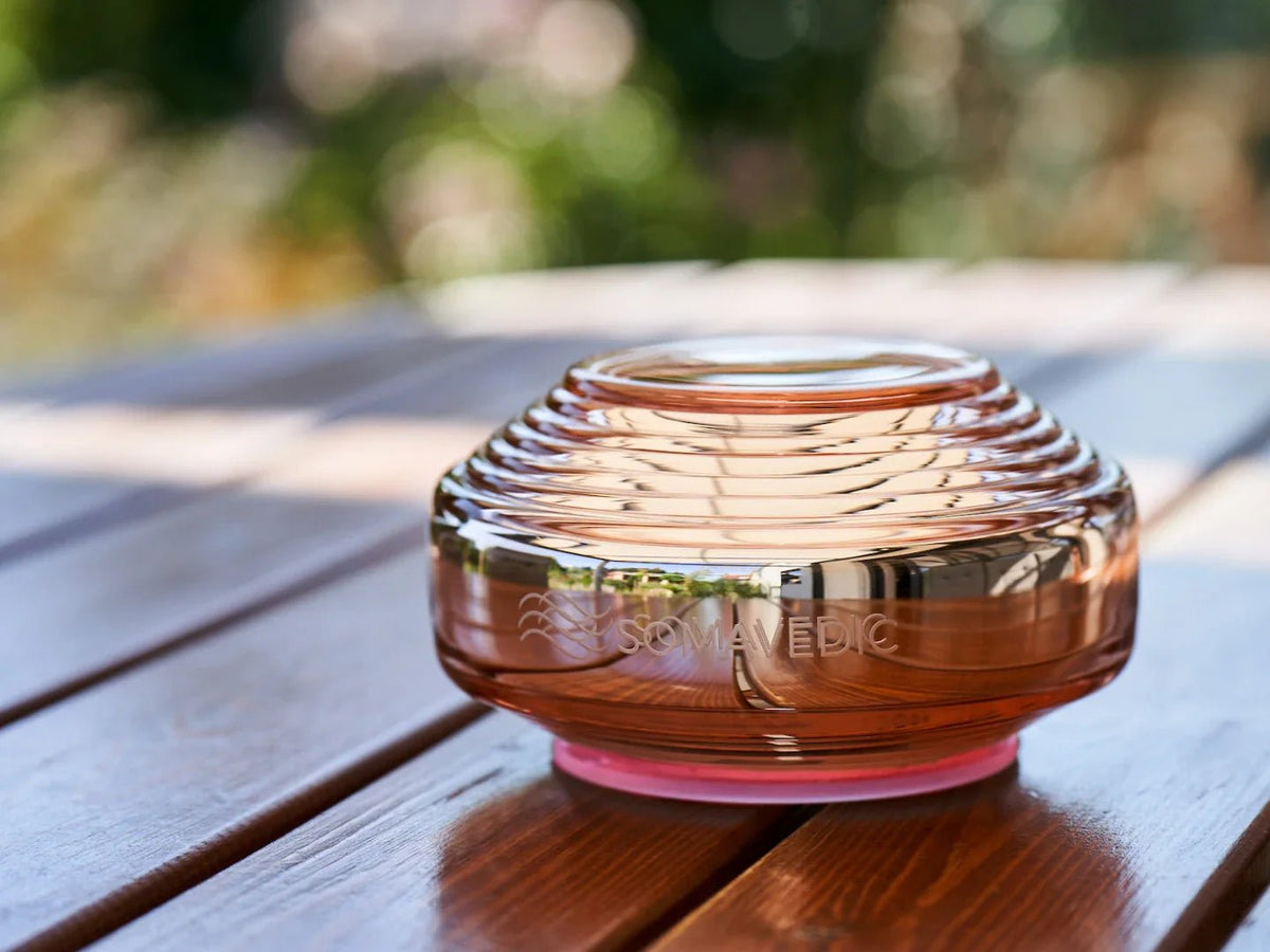 Somavedic Rosalin with a pink base glow on an outdoor wooden table