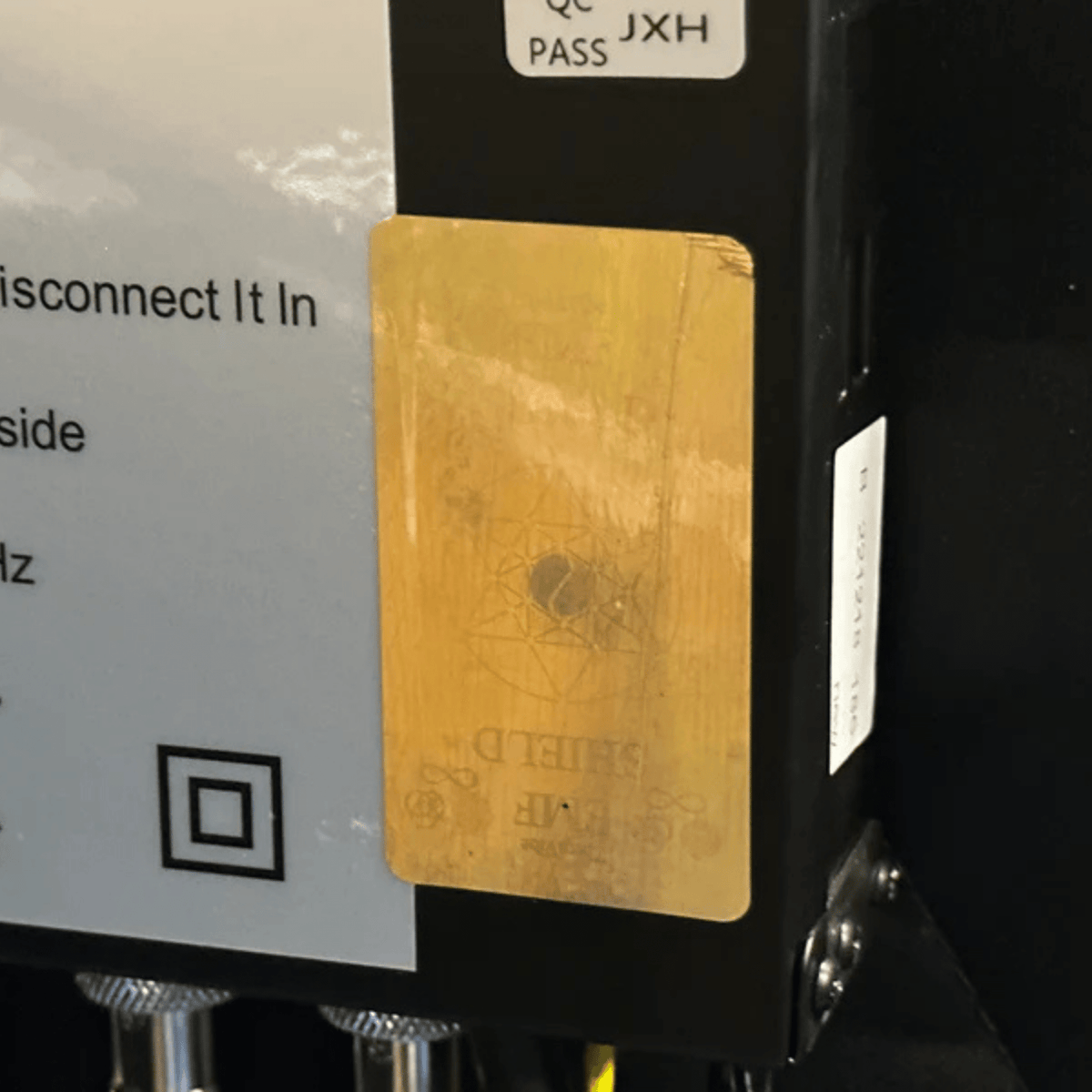 Therasage TheraProtect gold EMF protection sticker on the side of a black electronic device
