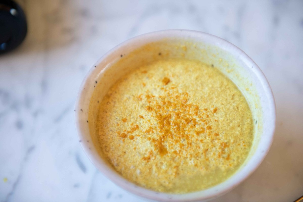 Bowl of golden latte dusted with turmeric on marble, made with Sun Potion Yin Power